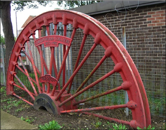 Figure 1: Pit winding wheels are often set as memorials to both killed workers and former collieries in these communities. This example, from Cortonwood Colliery, is adjacent to Brampton’s war memorial.